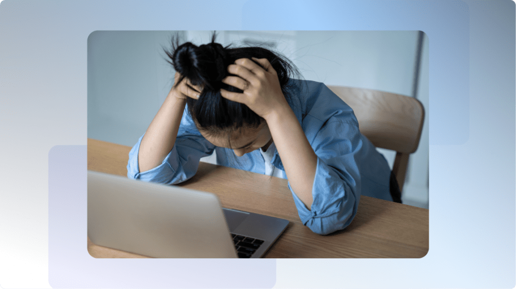 person in front of laptop with head down appearing in distress