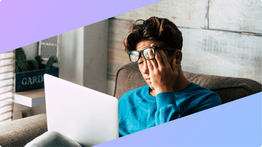 a person at their laptop, rubbing their eyes