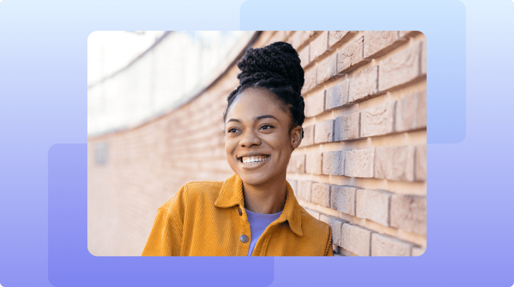 A woman leaning against a brick wall smiling